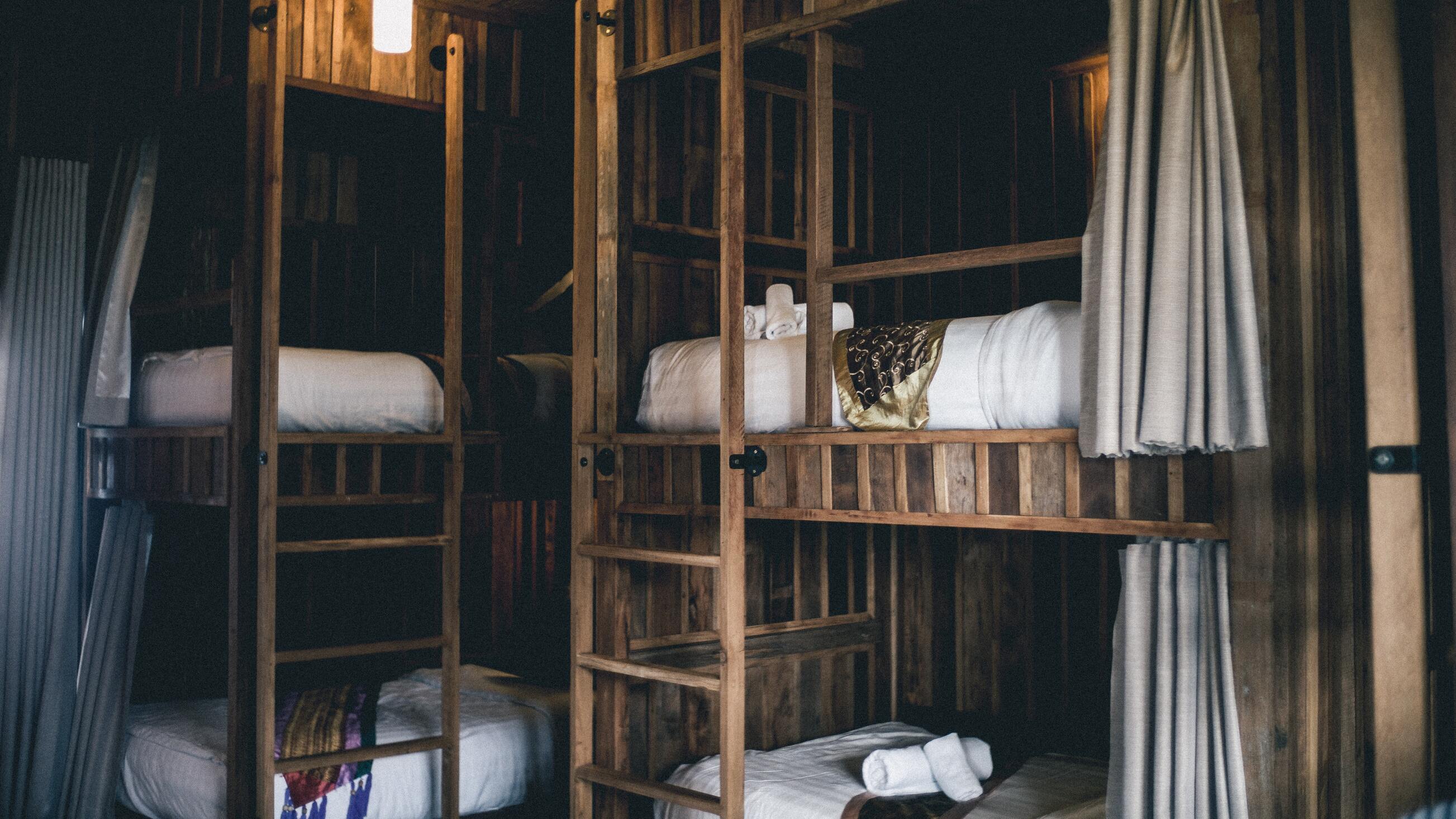 chambre style éco-lodge avec deux lits superposés disposant de rideaux. Structure et murs en bois brute